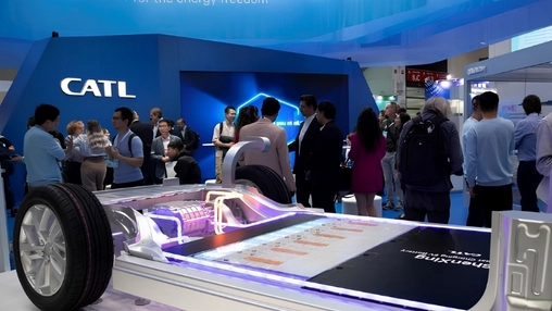 CATL exhibition featuring a glowing electric vehicle battery floor model with visitors at an industry show