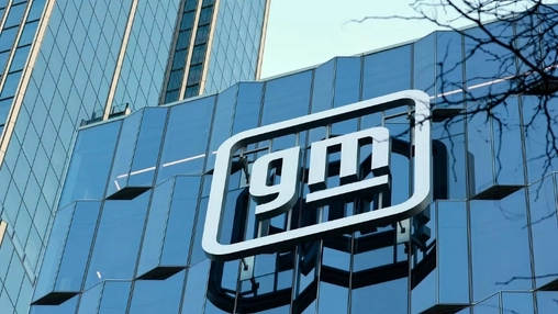 GM signage on a glass-panelled corporate tower with reflections of nearby buildings visible across the facade
